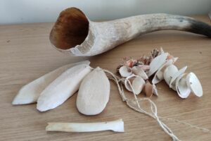 Replikate steinzeitlicher Instrumente: Knochenflöte, Schwirrhölzer, Horn und Muschelrassel